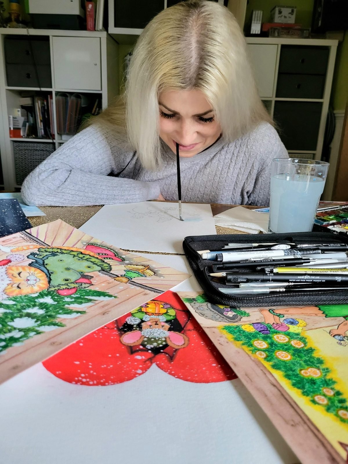Elīna Veinberga at her studio desk, painting one of her colourful illustrations